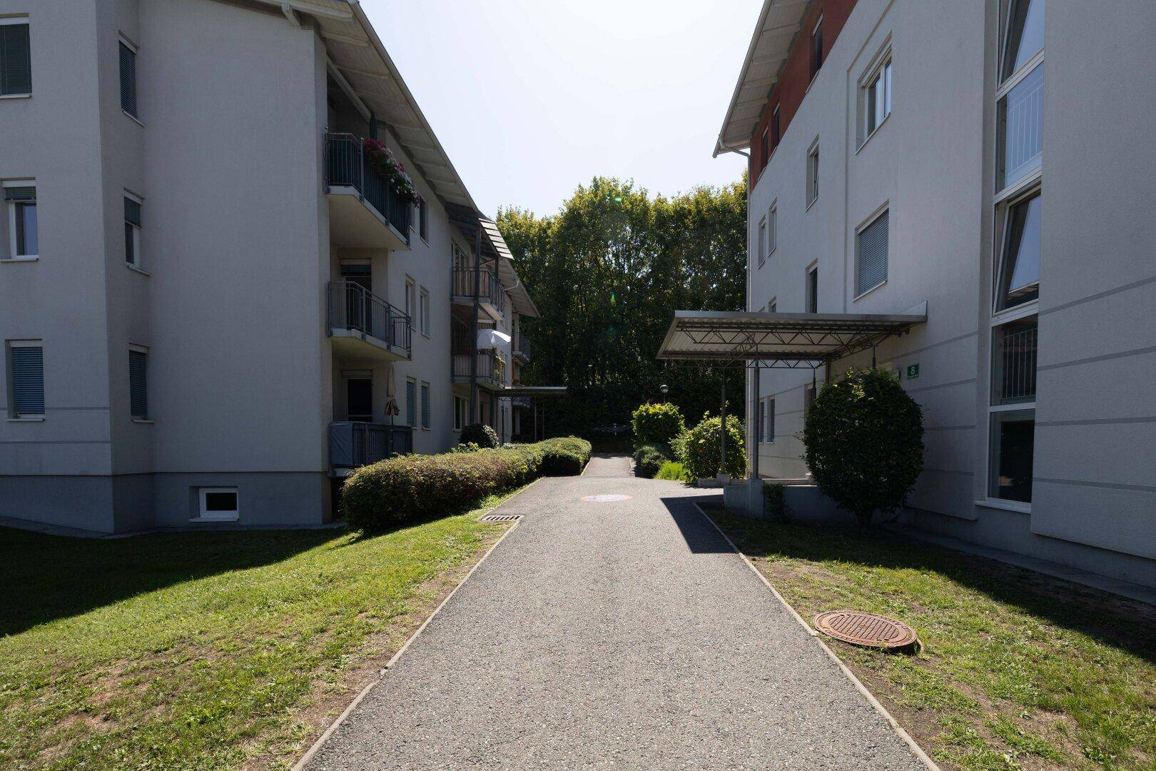 Außenansicht der Wohnanlage mit gepflegten Grünflächen und Zufahrtsweg.
