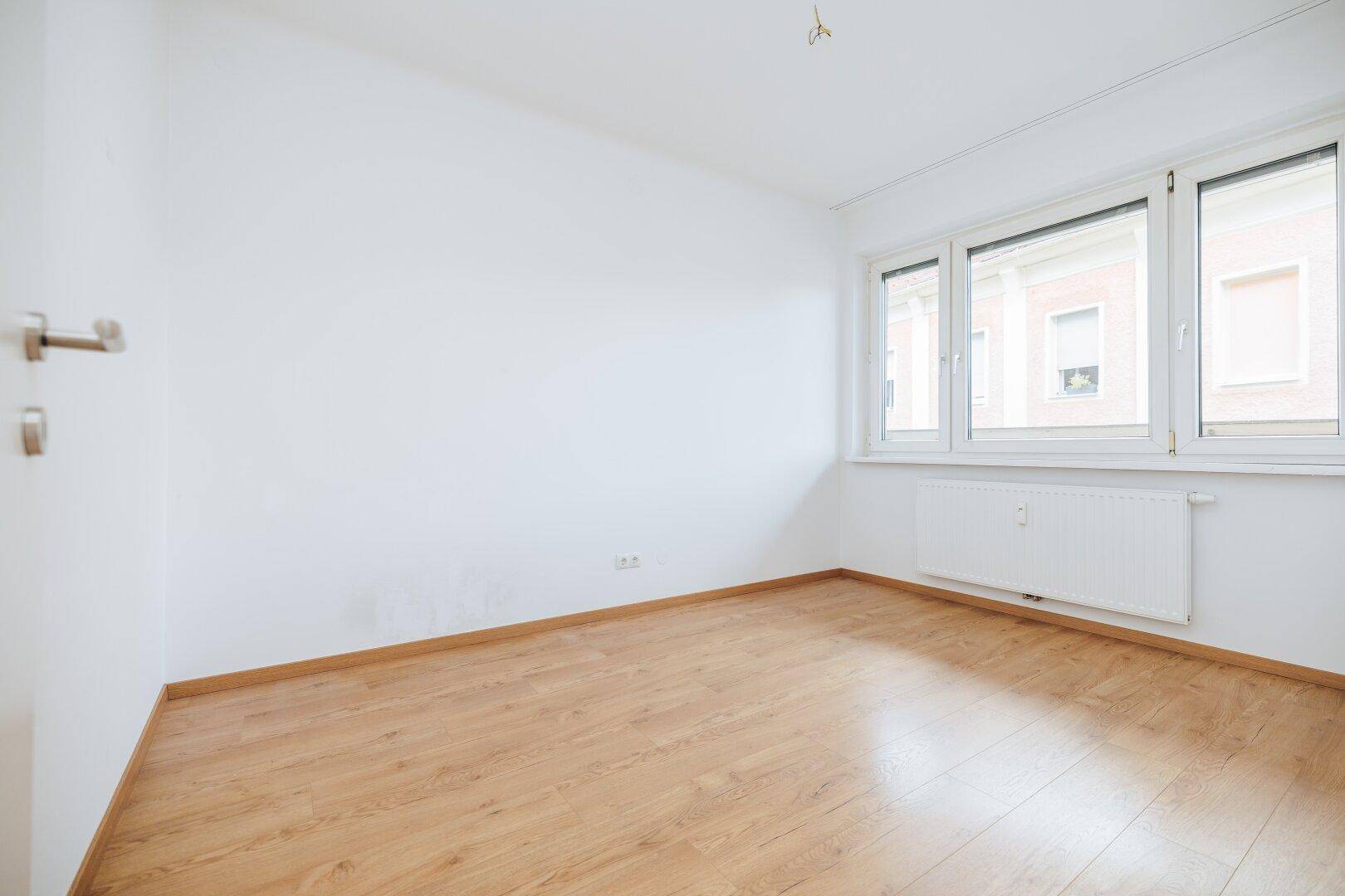 Geräumiges Schlafzimmer mit hellem Holzboden und großen Fenstern für viel Tageslicht.
