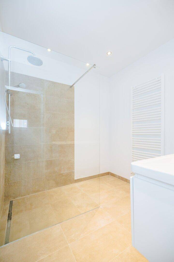 Geräumige begehbare Dusche mit Regenduschkopf und beheiztem Handtuchhalter im modernen Bad.