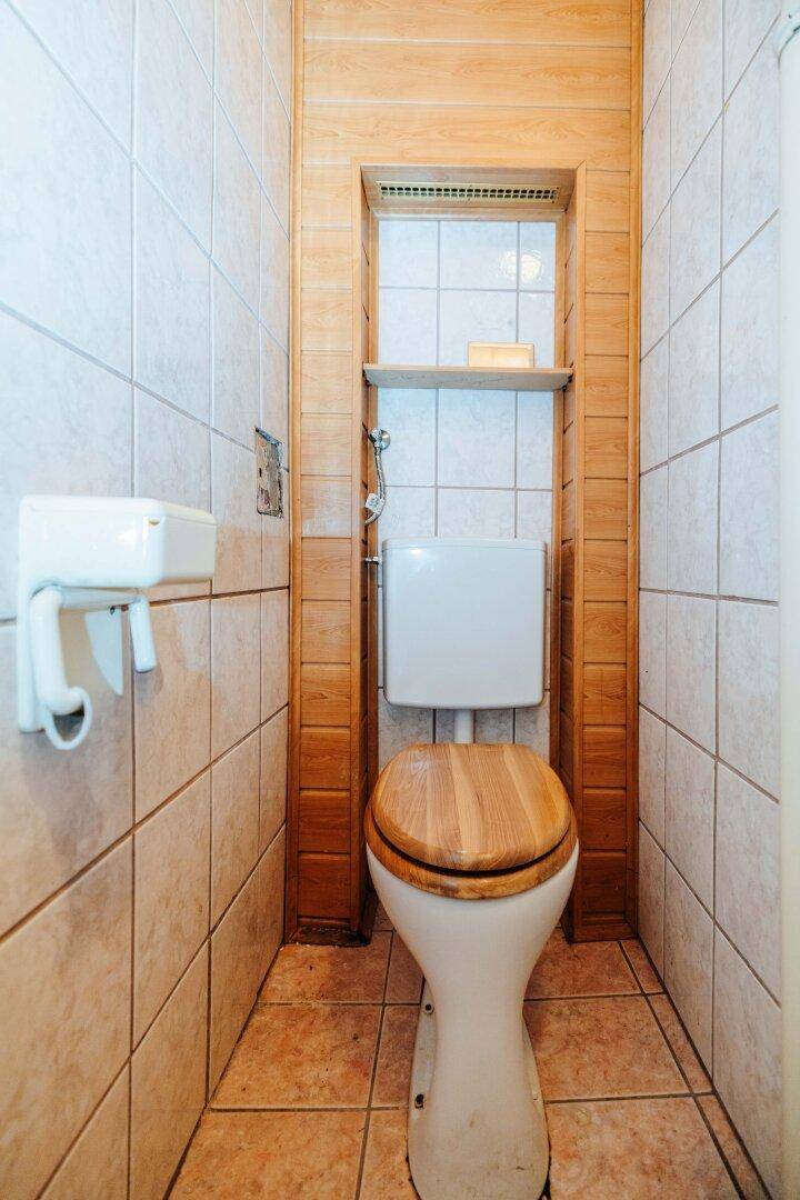 Kleines WC mit Fliesen, Holzvertäfelung und einfacher Toilette.