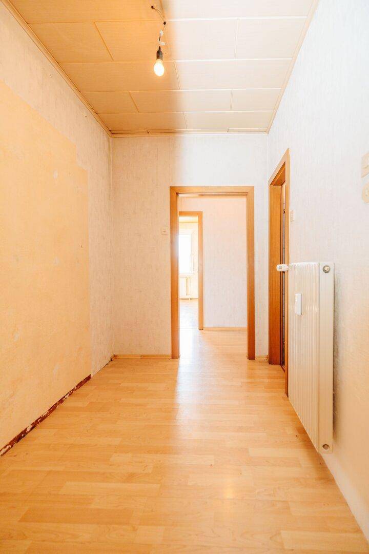 Heller Flur mit Laminatboden, Heizkörper und Blick in weitere Zimmer.