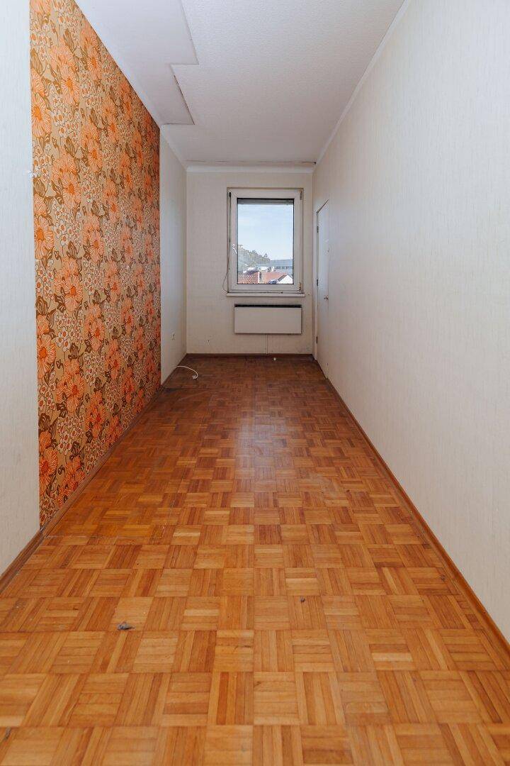 Langer Flur mit Parkettboden, floraler Tapete und Fenster am Ende.