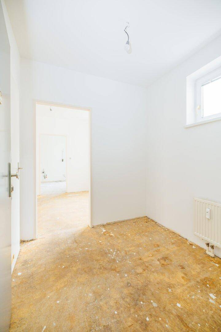 Heller, leerer Raum mit weiß gestrichenen Wänden und Fenster, bereit für neue Bodenbeläge.