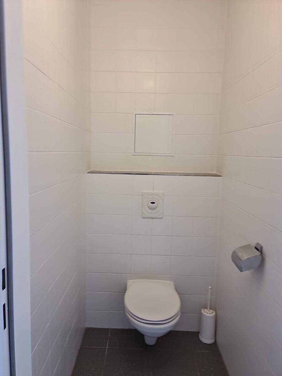 Modernes Gäste-WC mit weißen Wandfliesen und wandhängendem WC.