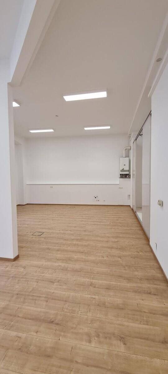 Heller Büroraum mit Laminatboden und an der Wand montierter Gastherme.