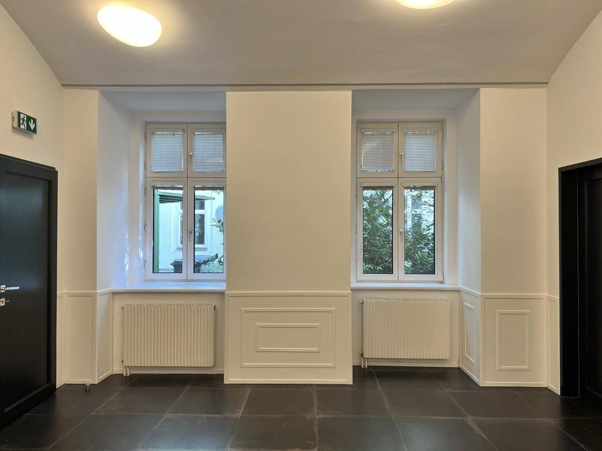 Geräumiger Flur mit zwei Fenstern, die einen Blick ins Grüne bieten, und klassischen Wandpaneelen.