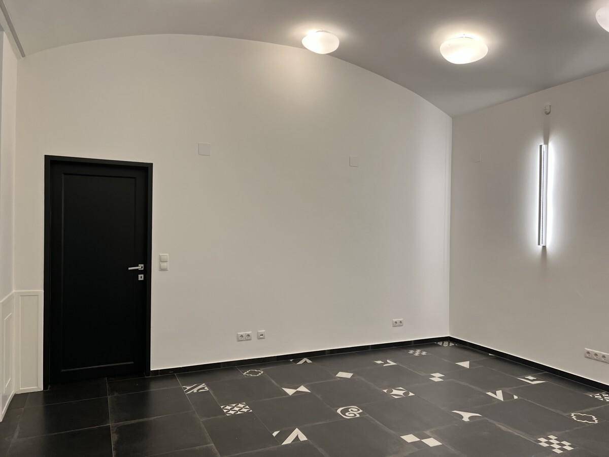 Heller Raum mit modernen Wandleuchten und einem auffälligen Fliesenboden in Schwarz-Weiß-Muster.