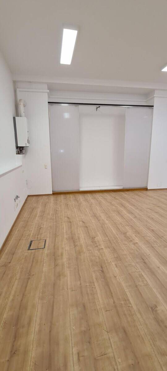 Geräumiger Bürobereich mit Laminatboden, Gastherme und Schiebetüren.