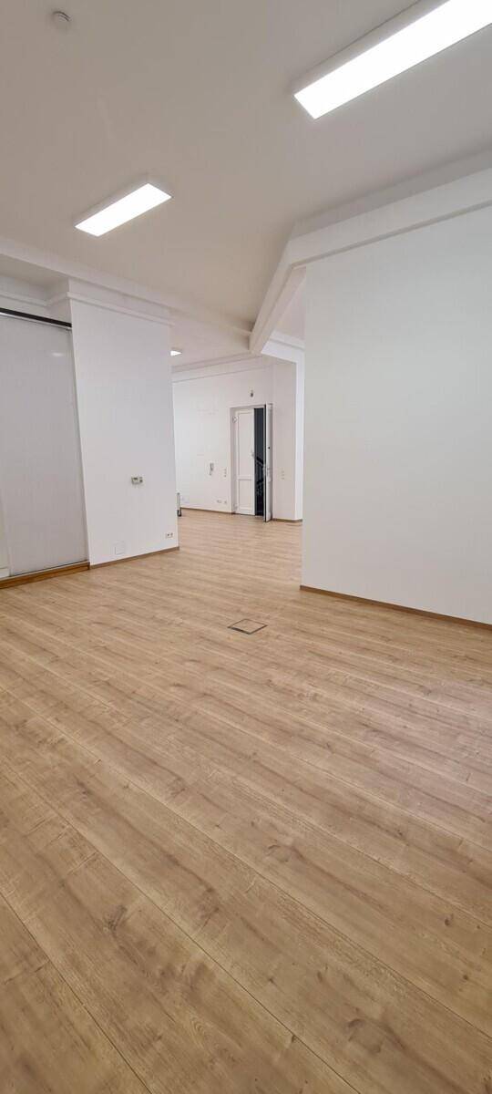 Offener Bürobereich mit hellem Laminatboden und Blick auf eine weitere Tür.