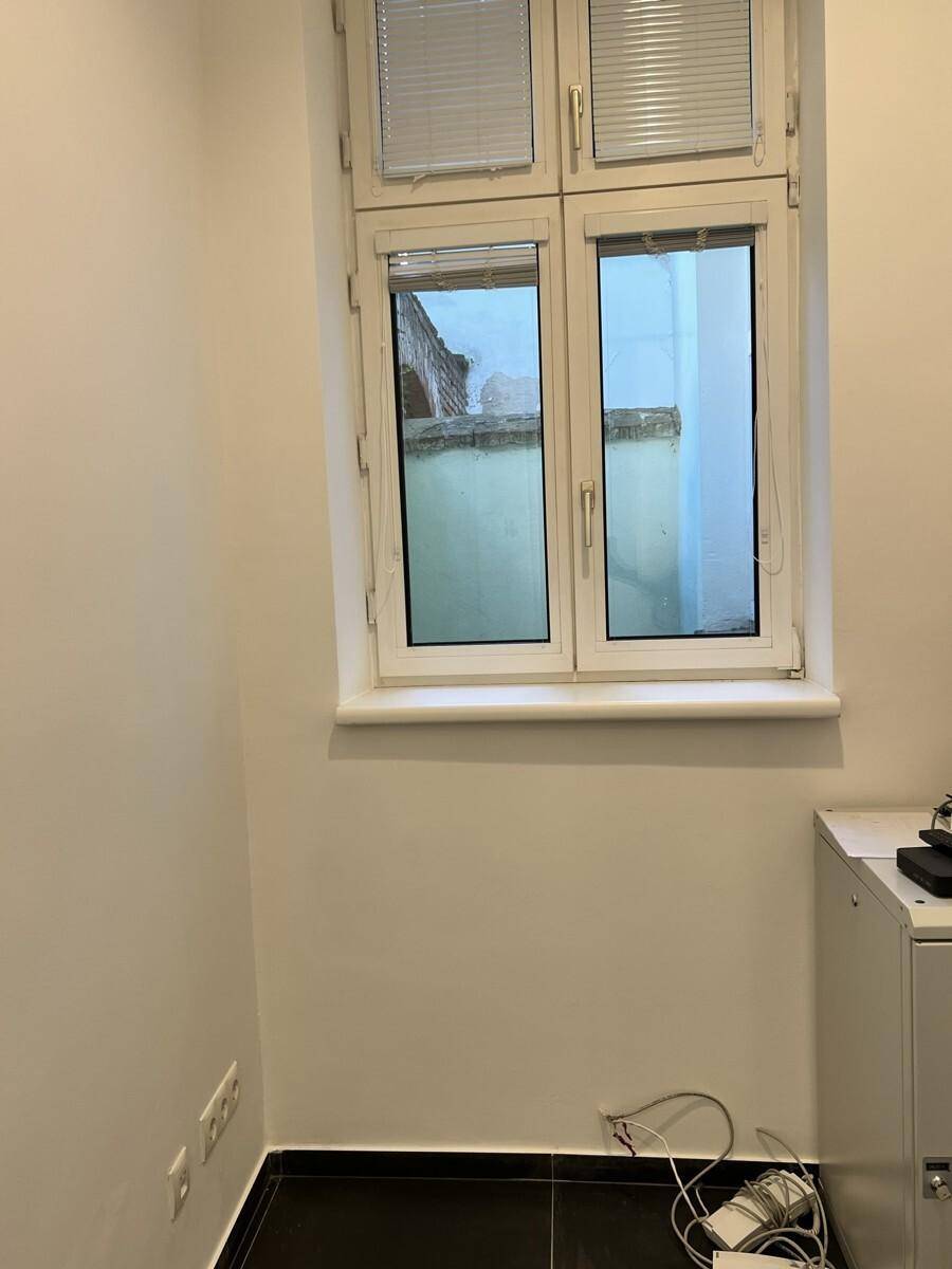 Kleiner Raum mit einem Fenster, das einen Blick auf einen Innenhof bietet, und Kabeln am Boden.