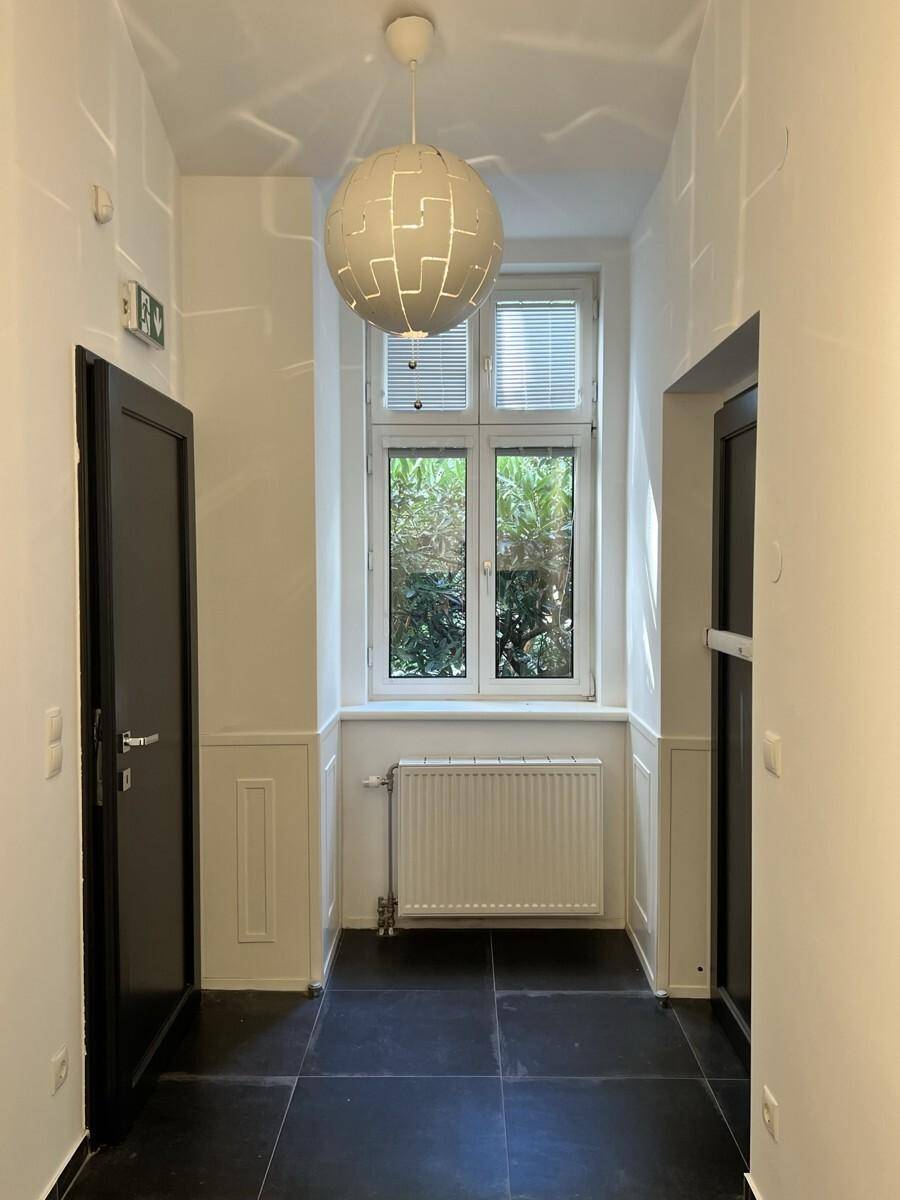 Heller Flur mit einem großen Fenster, das einen Blick ins Grüne bietet, und einer modernen Deckenleuchte.