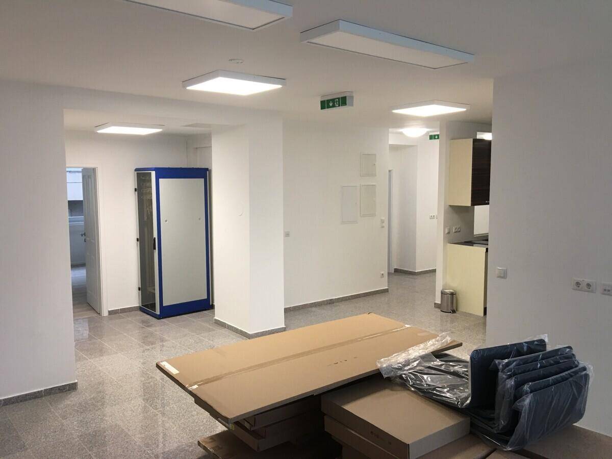 Großer offener Bürobereich mit integrierter Küchenzeile, Fliesenboden und Serverrack.