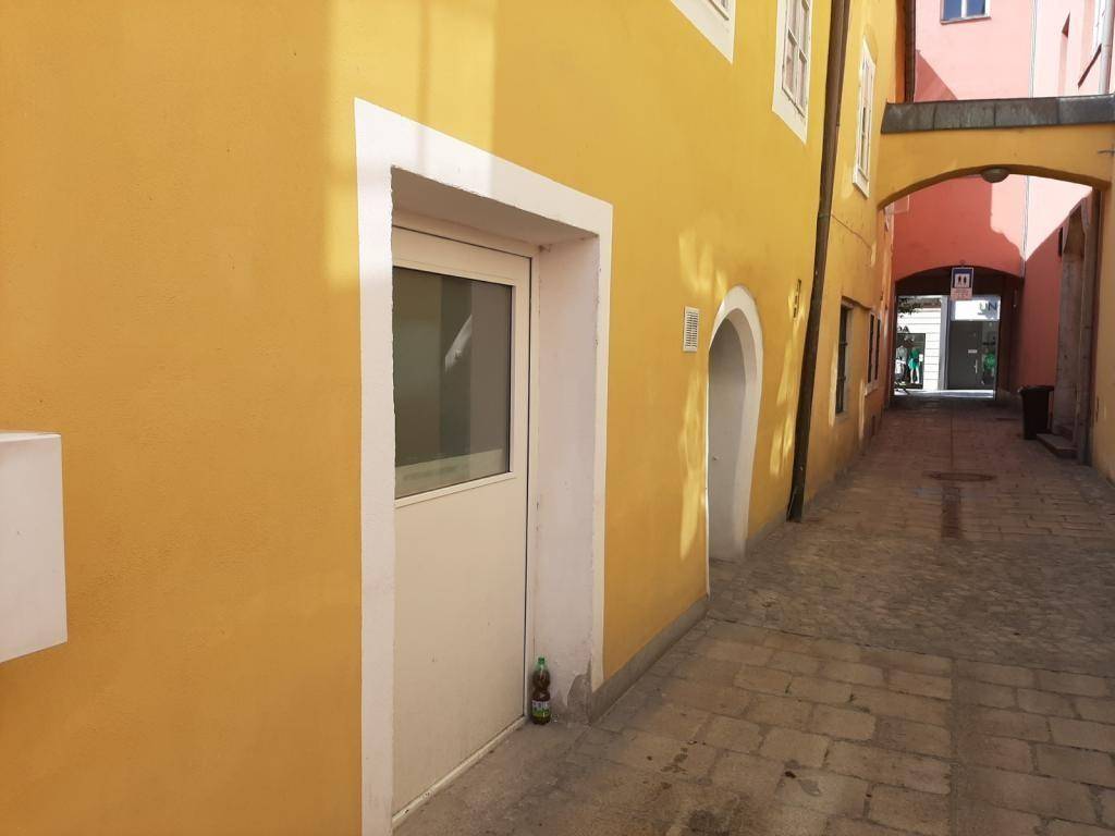 Enge Gasse mit gelb gestrichenen Gebäuden und einem Torbogen im Hintergrund.