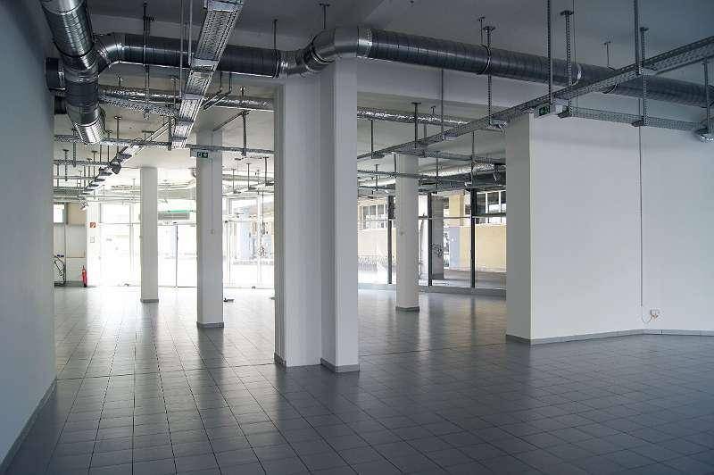 Weitläufiger, leerer Gewerberaum mit Säulen, Fliesenboden und offener Deckenkonstruktion, ideal für flexible Nutzung.