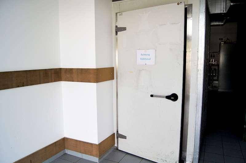Eingangstür zu einem Kühlraum mit Warnhinweis und einfacher, funktionaler Gestaltung im Gewerbebereich.