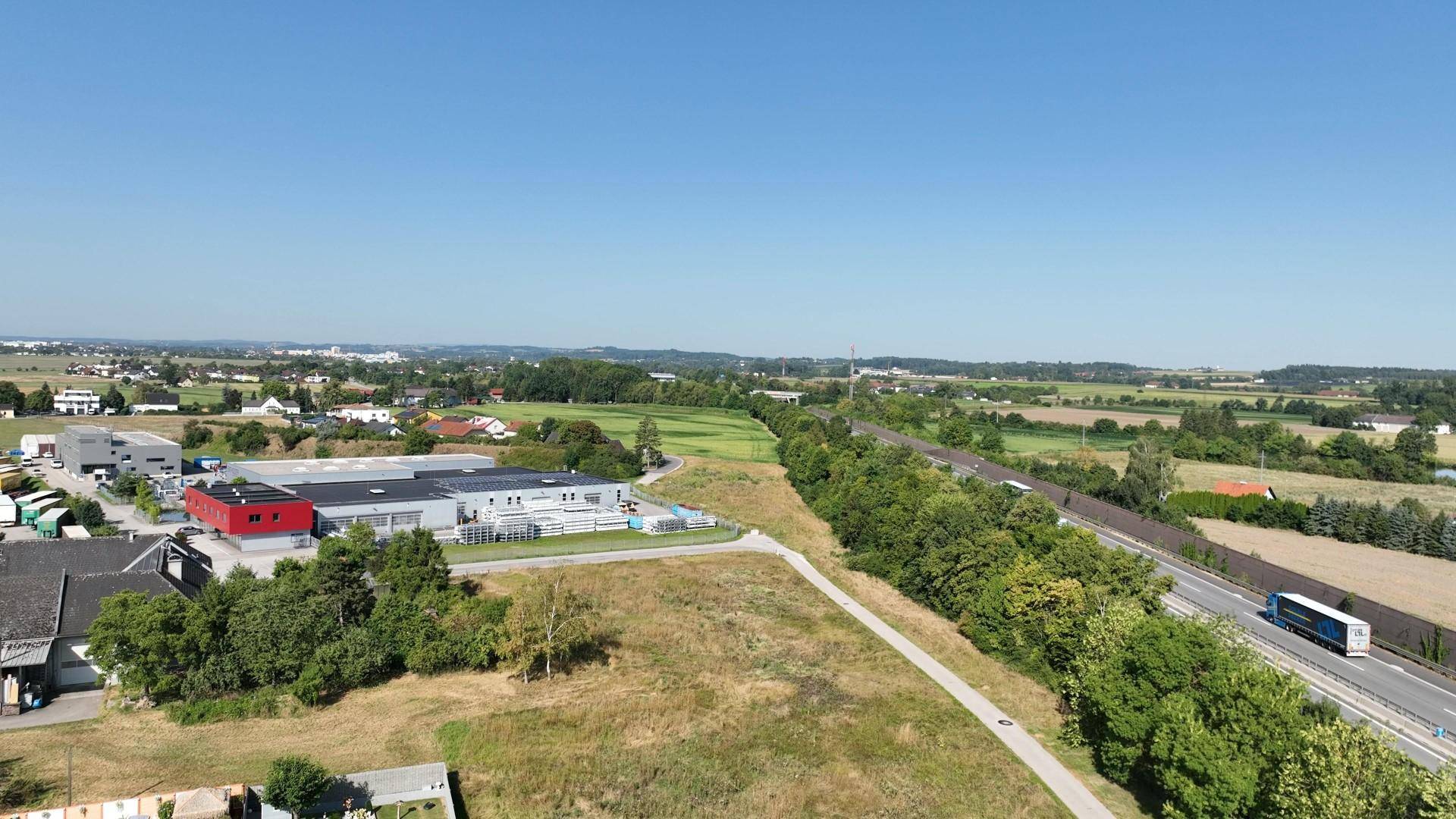 Weitwinkel-Luftaufnahme eines Gewerbegebiets mit Autobahnanbindung und ländlicher Umgebung.