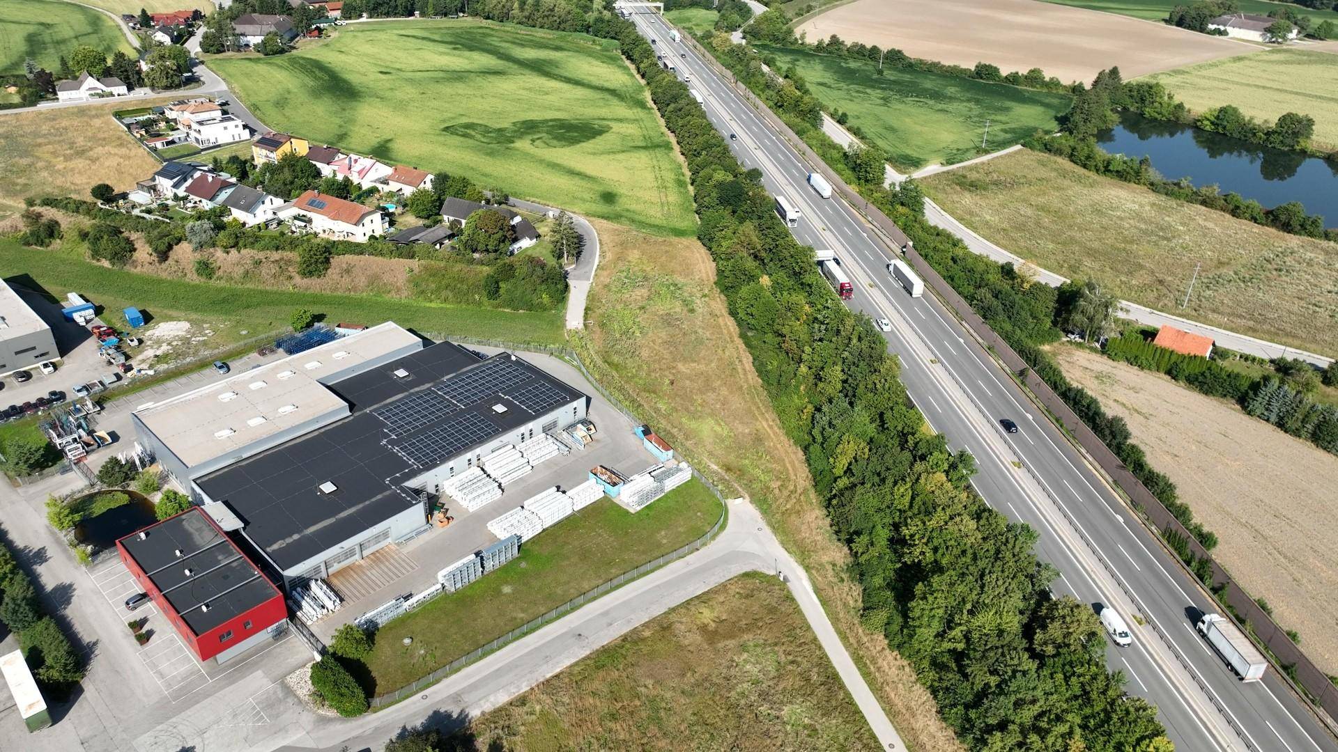 Luftaufnahme eines Gewerbegebäudes mit Solaranlage und angrenzender Autobahn A25.