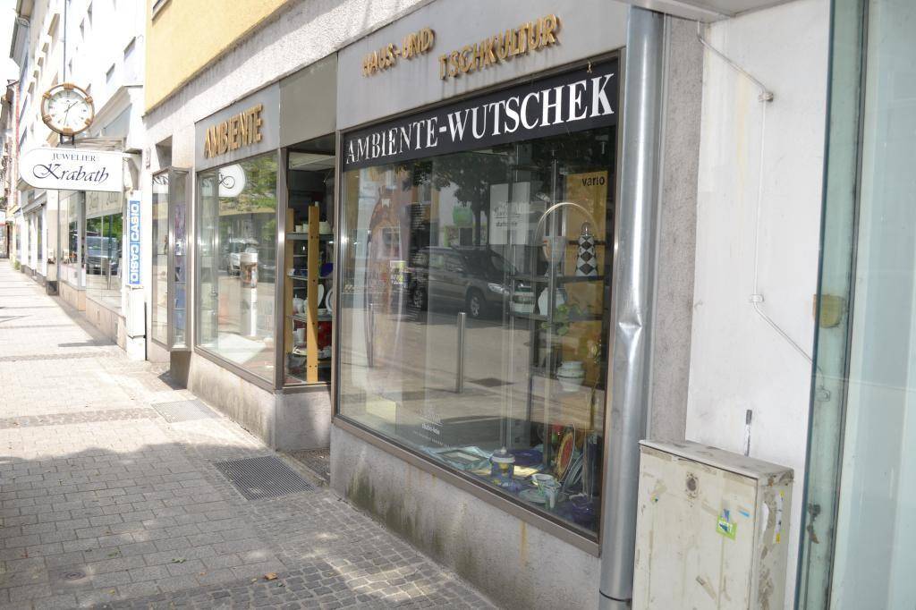 Ansicht der Geschäftsfassade mit großen Schaufenstern und einem Uhrengeschäft daneben.