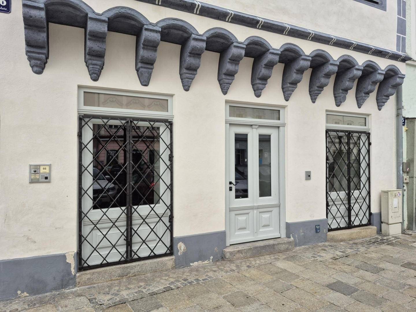 Erdgeschossfassade eines historischen Gebäudes mit Eingangstür und vergitterten Fenstern, gut erhalten.
