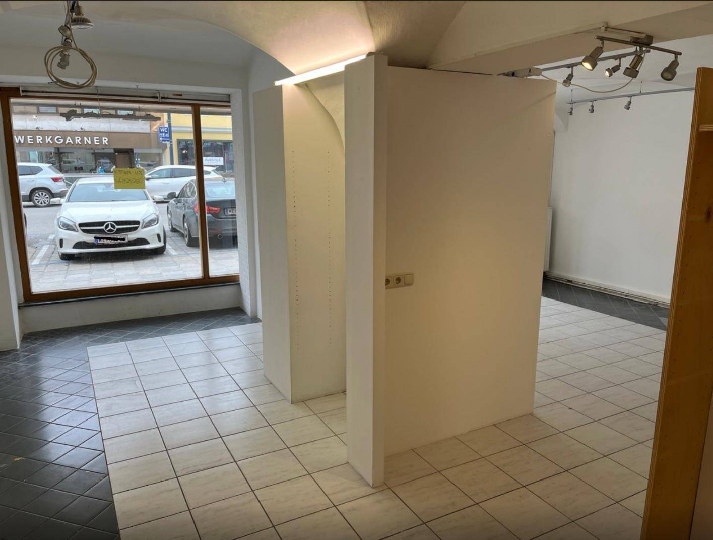 Ladenraum mit Fliesenboden, gewölbter Decke und Blick auf die Straße durch die großen Schaufenster.