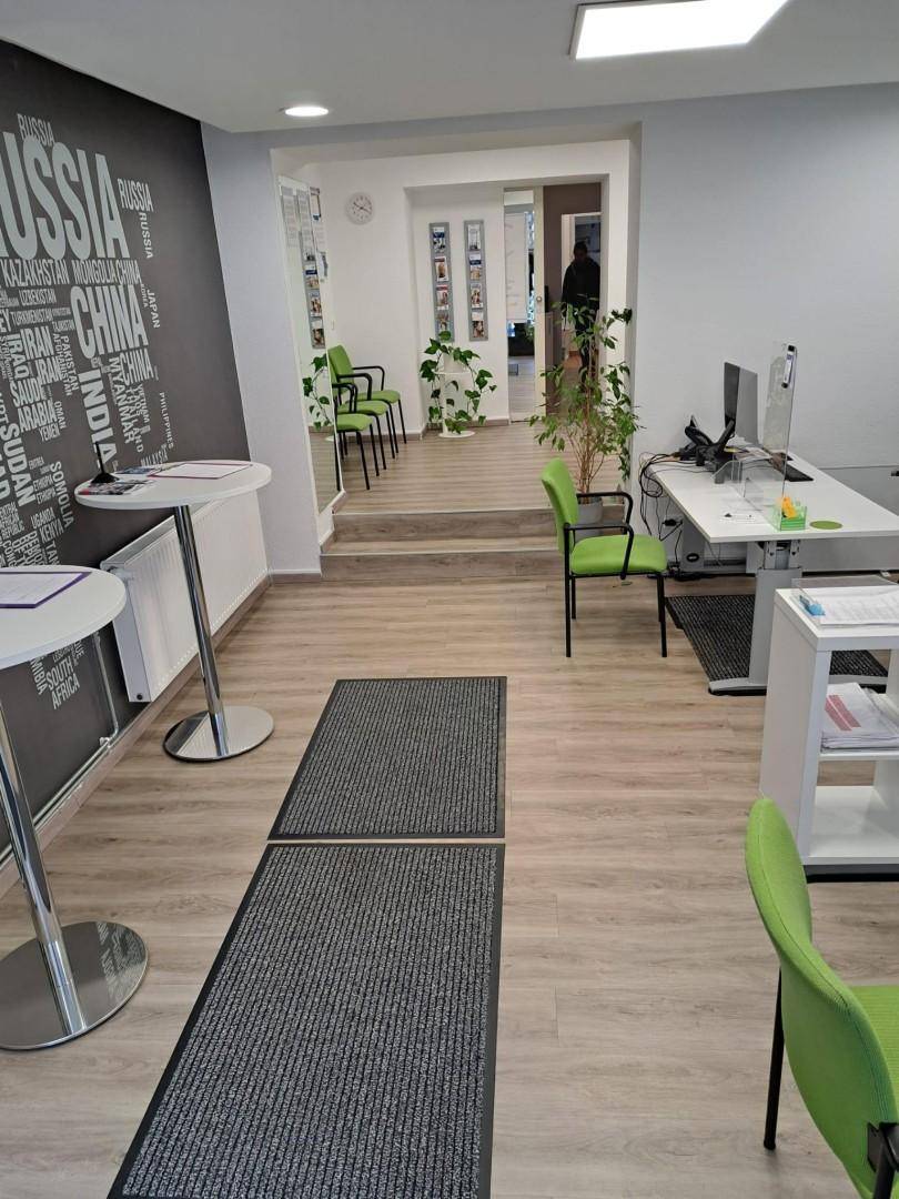 Büro mit Weltkarten-Wanddekoration, Stehtischen und Blick auf einen erhöhten Wartebereich.