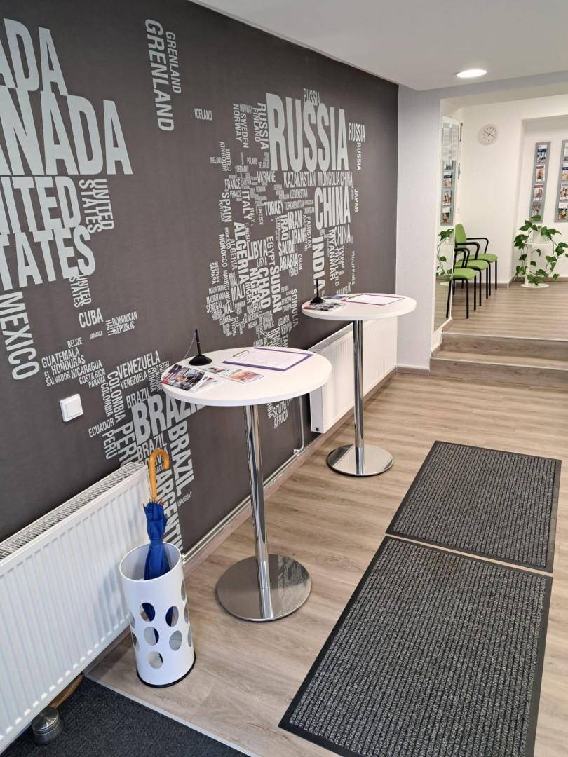 Büro-Empfangsbereich mit Weltkarten-Wanddekoration, Stehtischen und Heizkörper.
