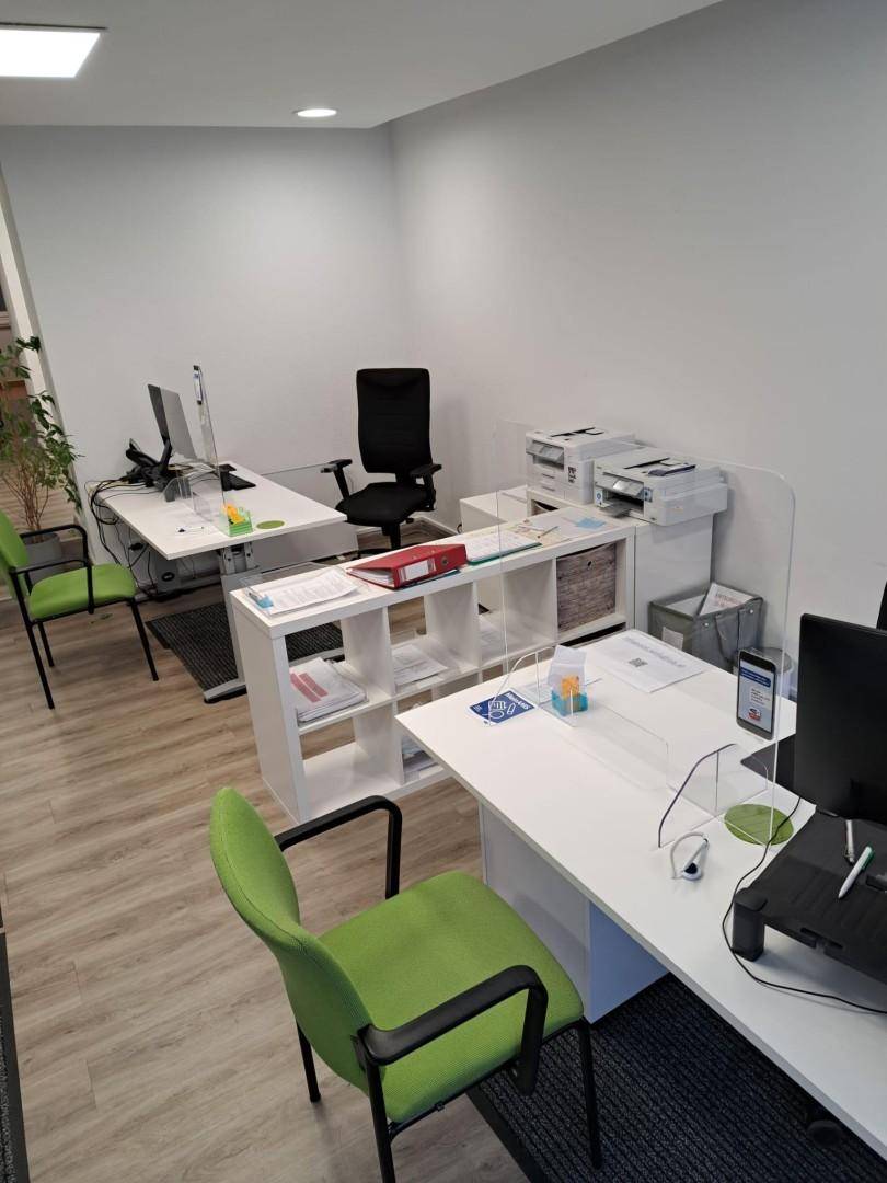 Moderner Büroraum mit mehreren Arbeitsplätzen, Druckern und hellen Möbeln, gut organisiert und funktional.