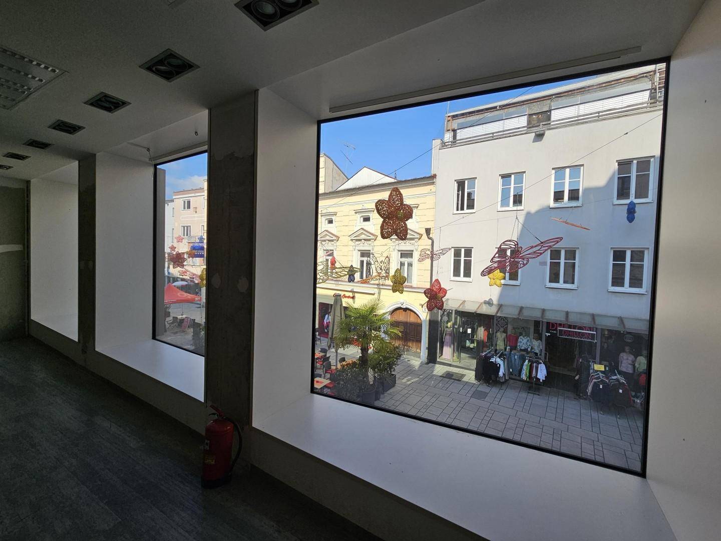 Blick aus den großen Fenstern eines Gewerberaums auf die belebte Einkaufsstraße.