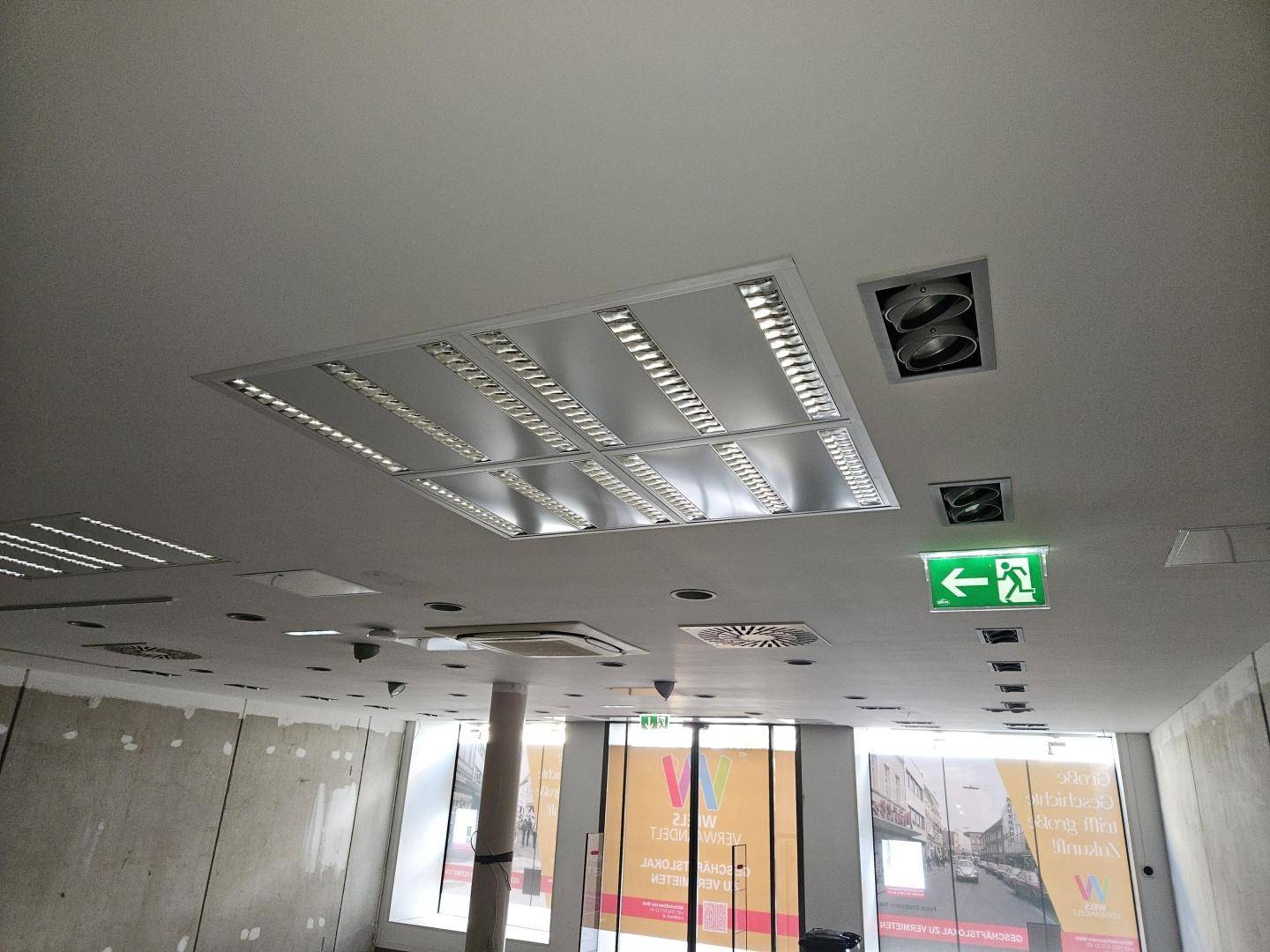 Deckenansicht eines Gewerberaums mit moderner Beleuchtung und Lüftungssystemen.