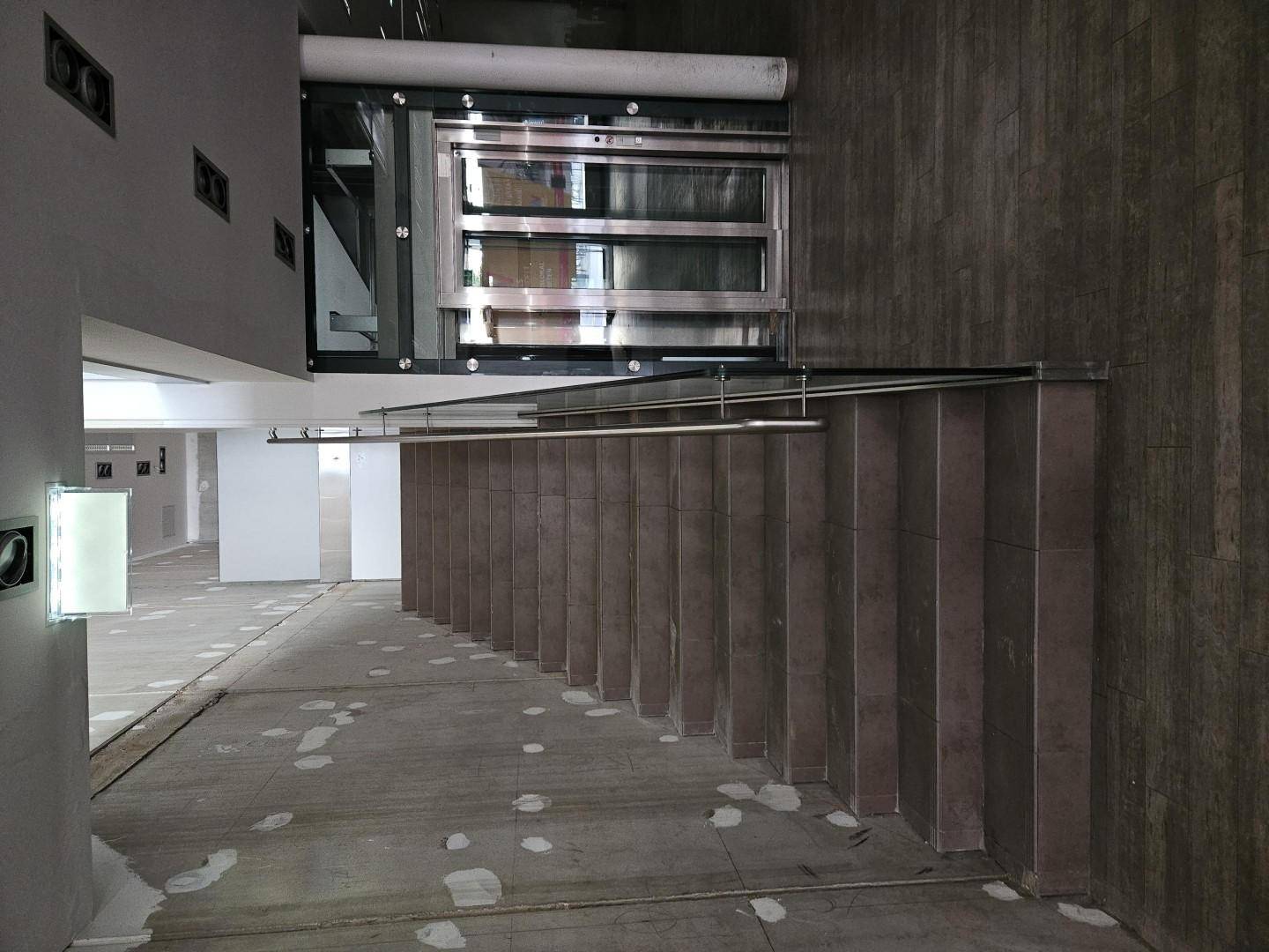 Treppenaufgang mit Fliesenstufen und moderner Glasbrüstung in einem Gewerbegebäude.