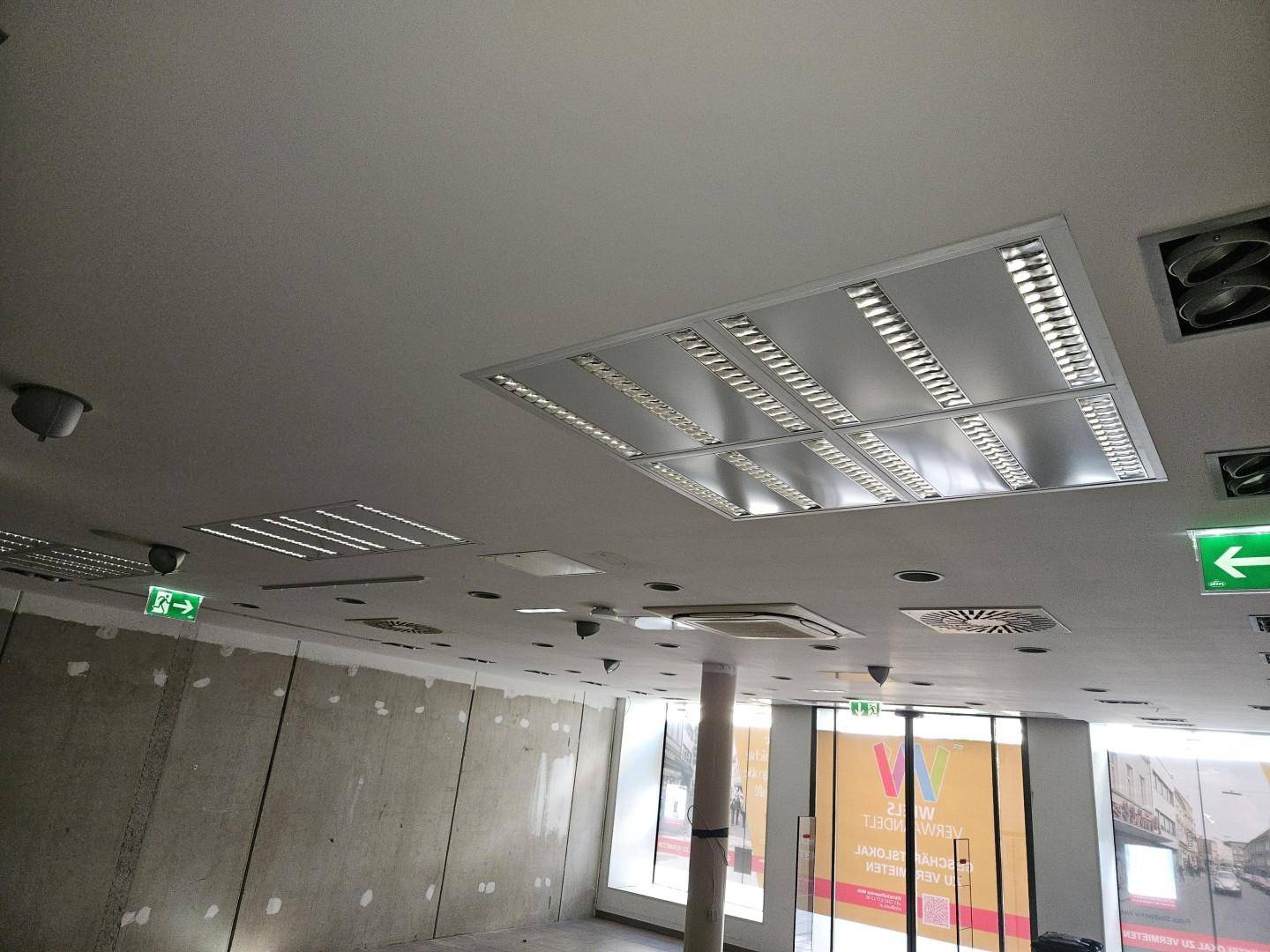 Deckenansicht eines Gewerberaums mit integrierter Beleuchtung, Lüftung und Sprinkleranlagen.