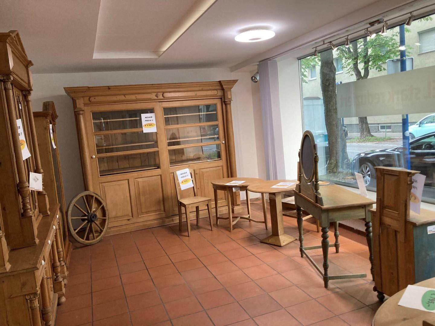 Verkaufsraum mit traditionellen Holzmöbeln, Terrakotta-Fliesenboden und großen Schaufenstern.