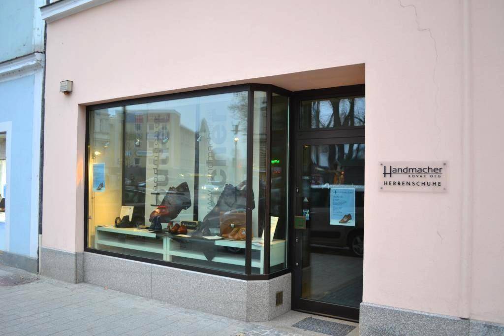 Eingangsbereich und Schaufenster eines Schuhgeschäfts mit der Aufschrift 'Handmacher Herrenschuhe'.