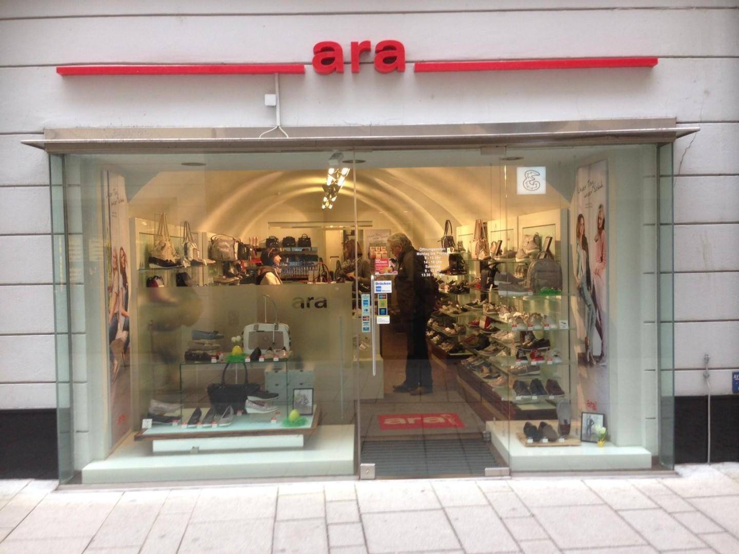 Blick in das Schuhgeschäft mit Kunden, Schuhregalen und einer gewölbten Deckenstruktur.