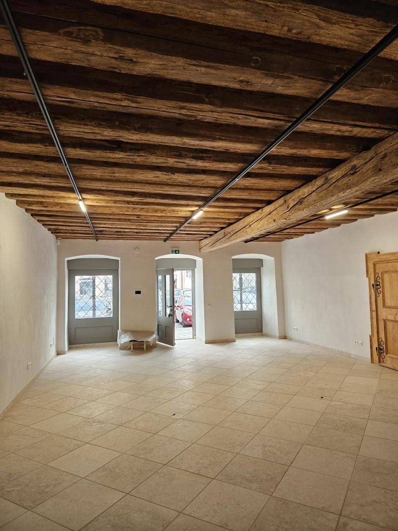 Heller Raum mit beeindruckender Holzbalkendecke und Fliesenboden, der durch mehrere Fenster gut belichtet ist.