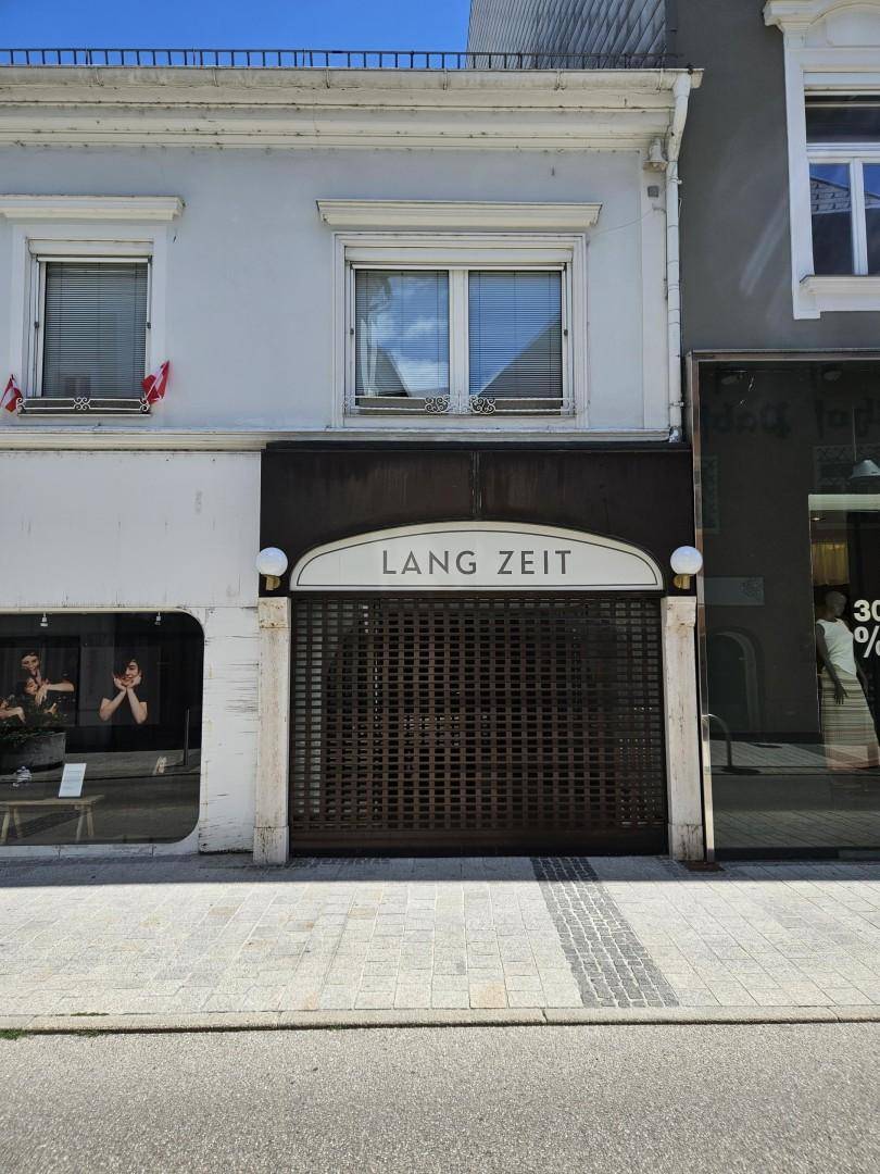 Fassade eines Geschäftsgebäudes mit geschlossenem Ladenlokal und Wohnungen darüber, an einer städtischen Straße gelegen.