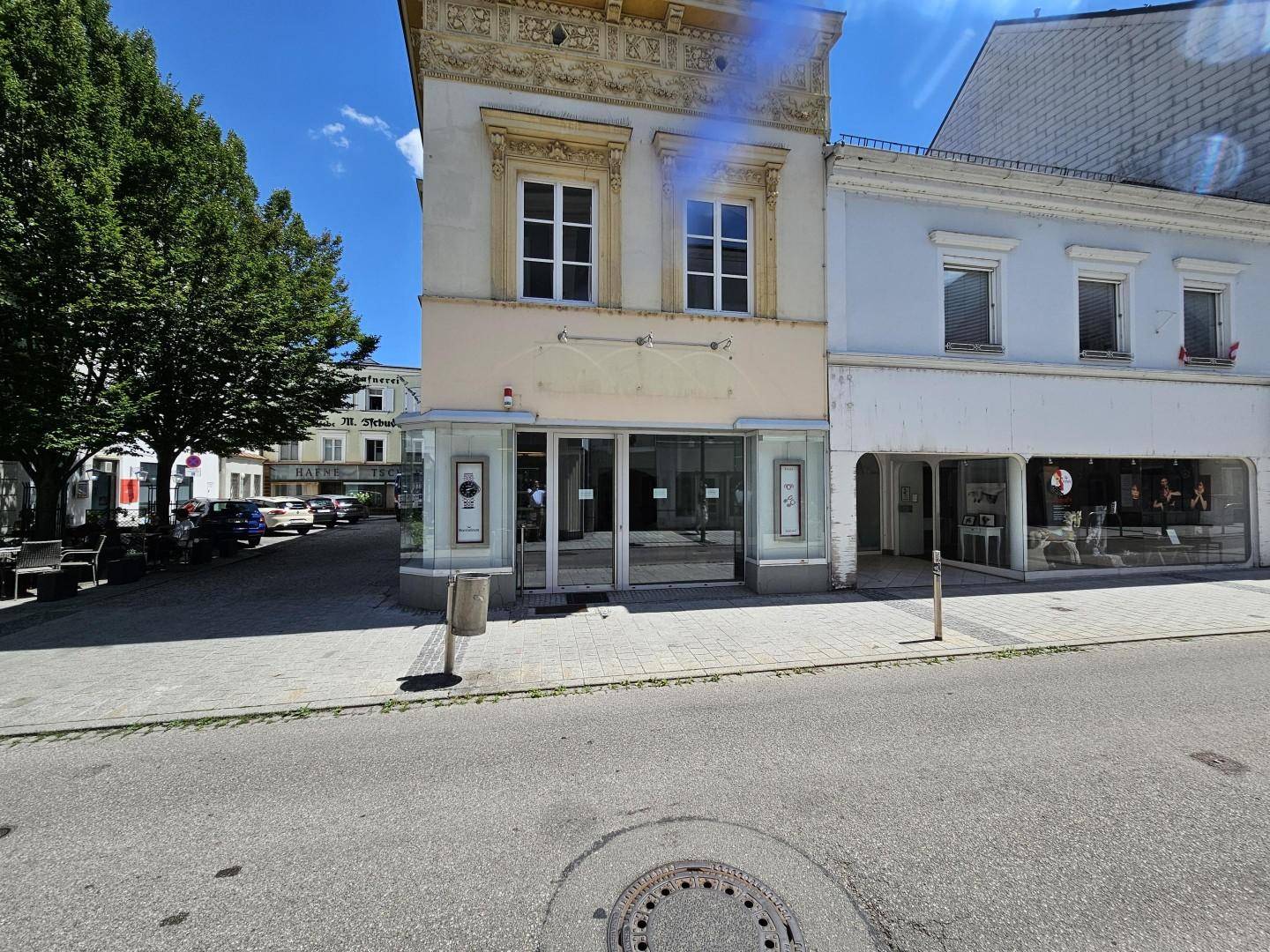 Ansicht der Ladenfront eines historischen Gebäudes mit großen Schaufenstern und Bürgersteig.