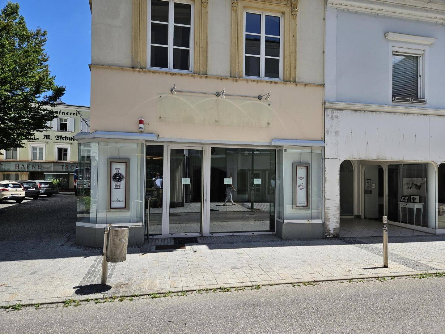 Eingangsbereich eines Geschäfts mit großen Glasfronten und Schaufenstern in einem historischen Gebäude.