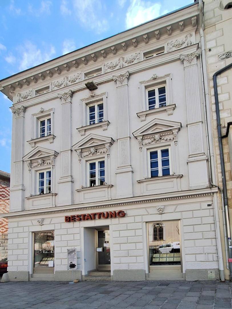 Vorderansicht eines historischen Gebäudes mit reich verzierten Fenstern und Fassadendetails.