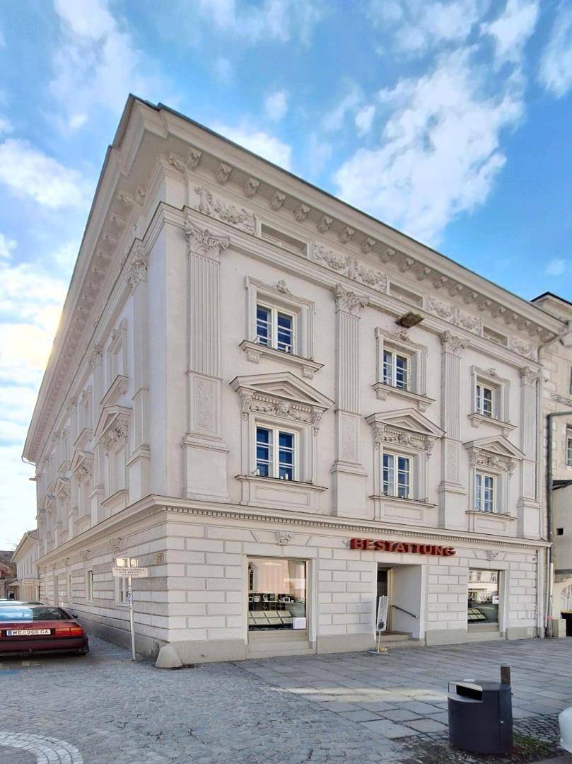 Elegantes historisches Gebäude mit weißer Fassade und klassischen Verzierungen an einer städtischen Straße.