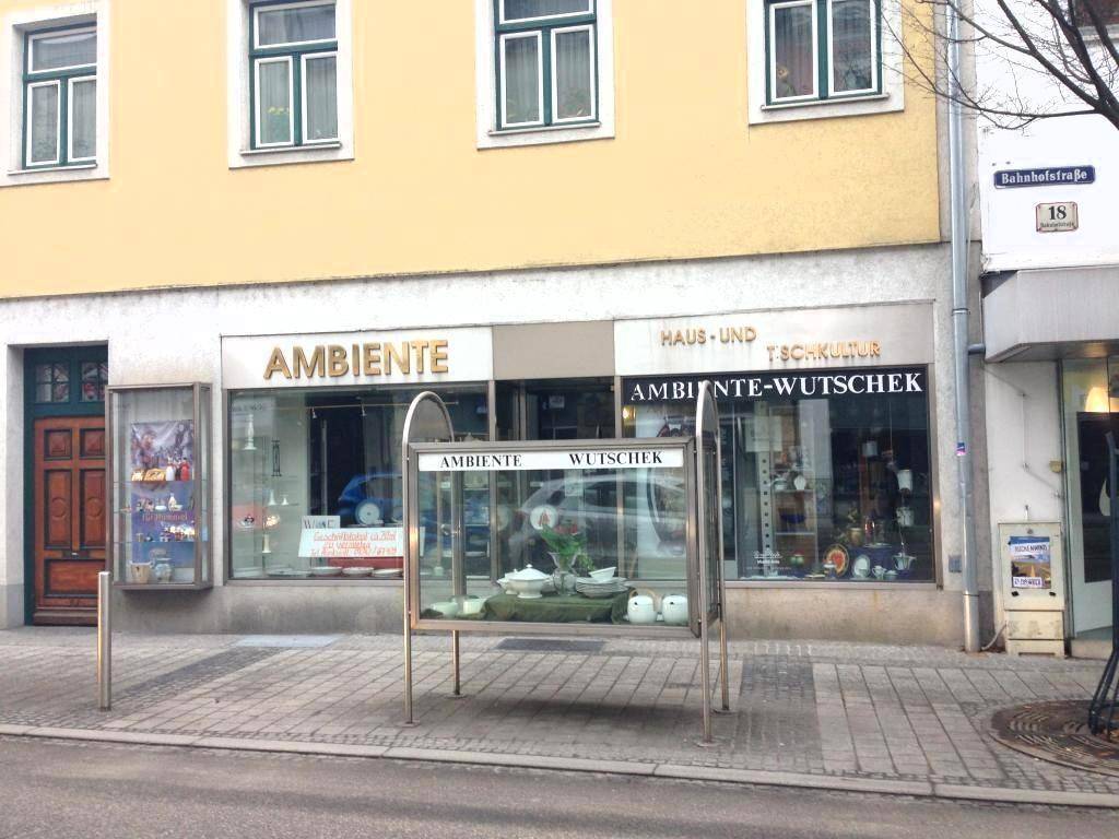 Gelbe Gebäudefassade mit großen Schaufenstern eines Einzelhandelsgeschäfts und traditionellen Fenstern im Obergeschoss.