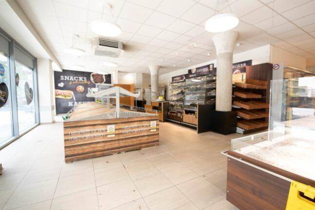 Bereich für Backwaren und Snacks in einem Supermarkt mit Holzelementen und großen Fenstern.