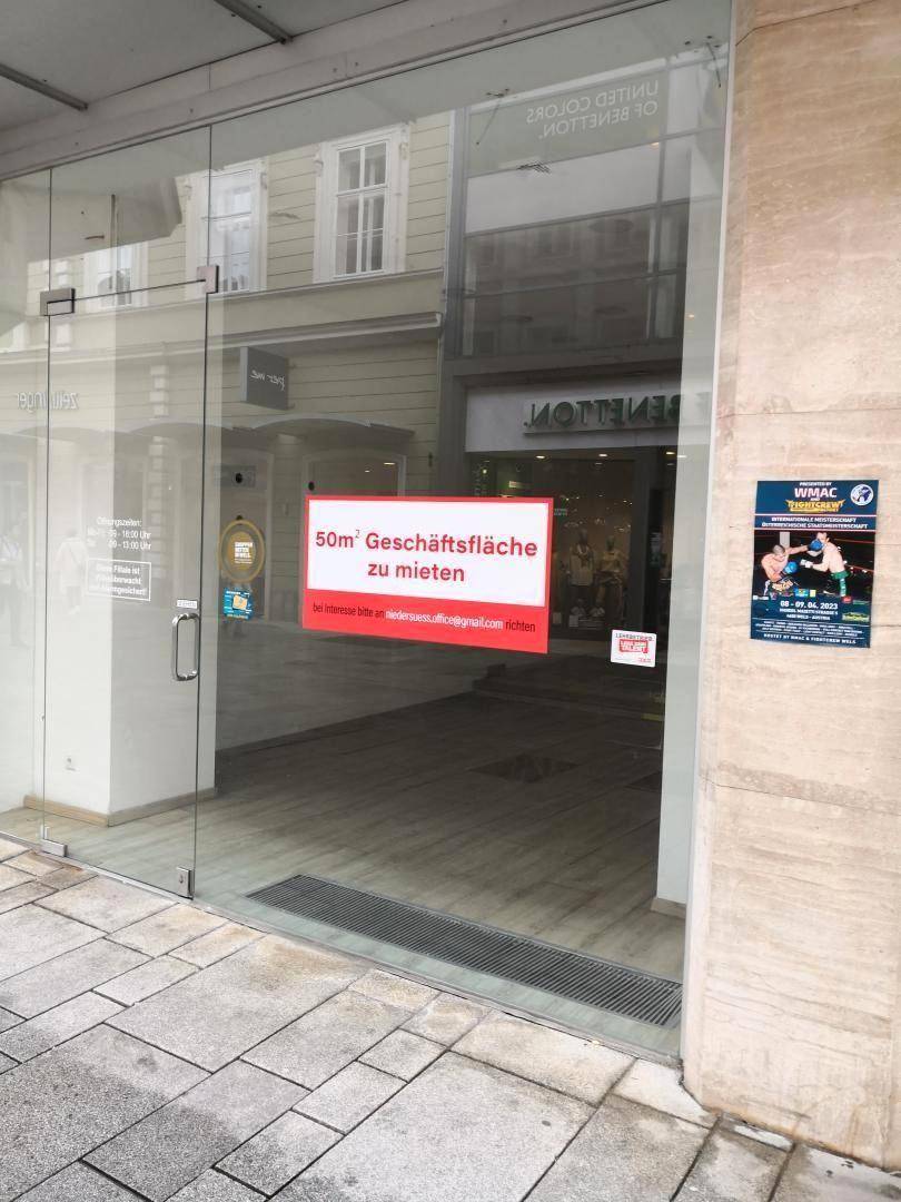 Eingangsbereich eines Geschäfts mit großer Glasfassade und einem Schild, das 50m² Geschäftsfläche zur Miete anzeigt.