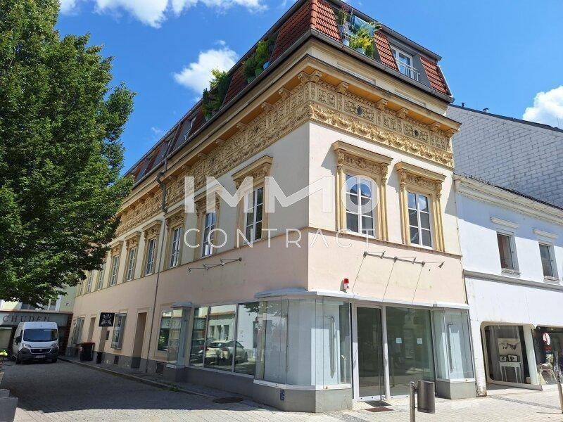Detailansicht eines historischen Gebäudes mit reich verzierten Fenstern und einer Dachterrasse.