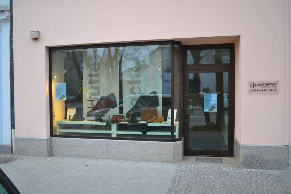 Nahaufnahme des Eingangs und Schaufensters eines Schuhgeschäfts mit 'Handmacher Herrenschuhe'.