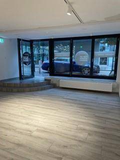 Geräumiger Gewerberaum mit großen Glasfronten, die viel Tageslicht hereinlassen und Blick auf die Straße bieten.