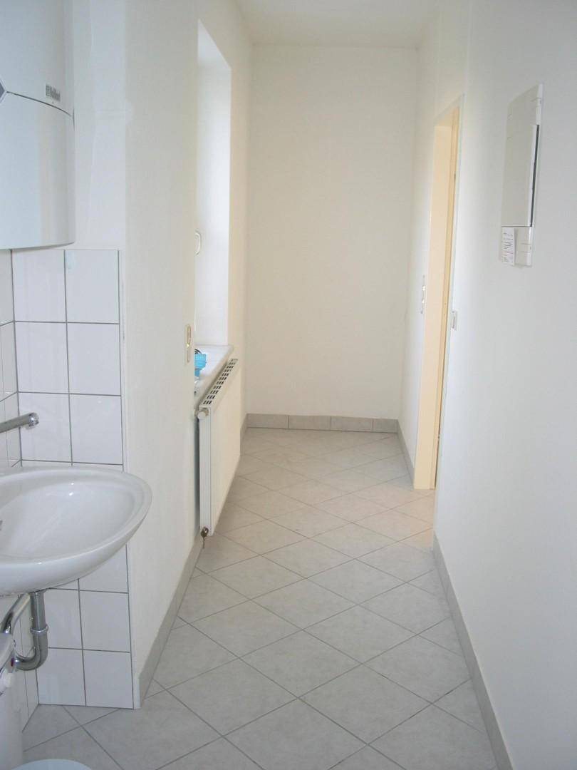 Heller Eingangsbereich mit Fliesenboden, Waschbecken und einem Fenster für Tageslicht.