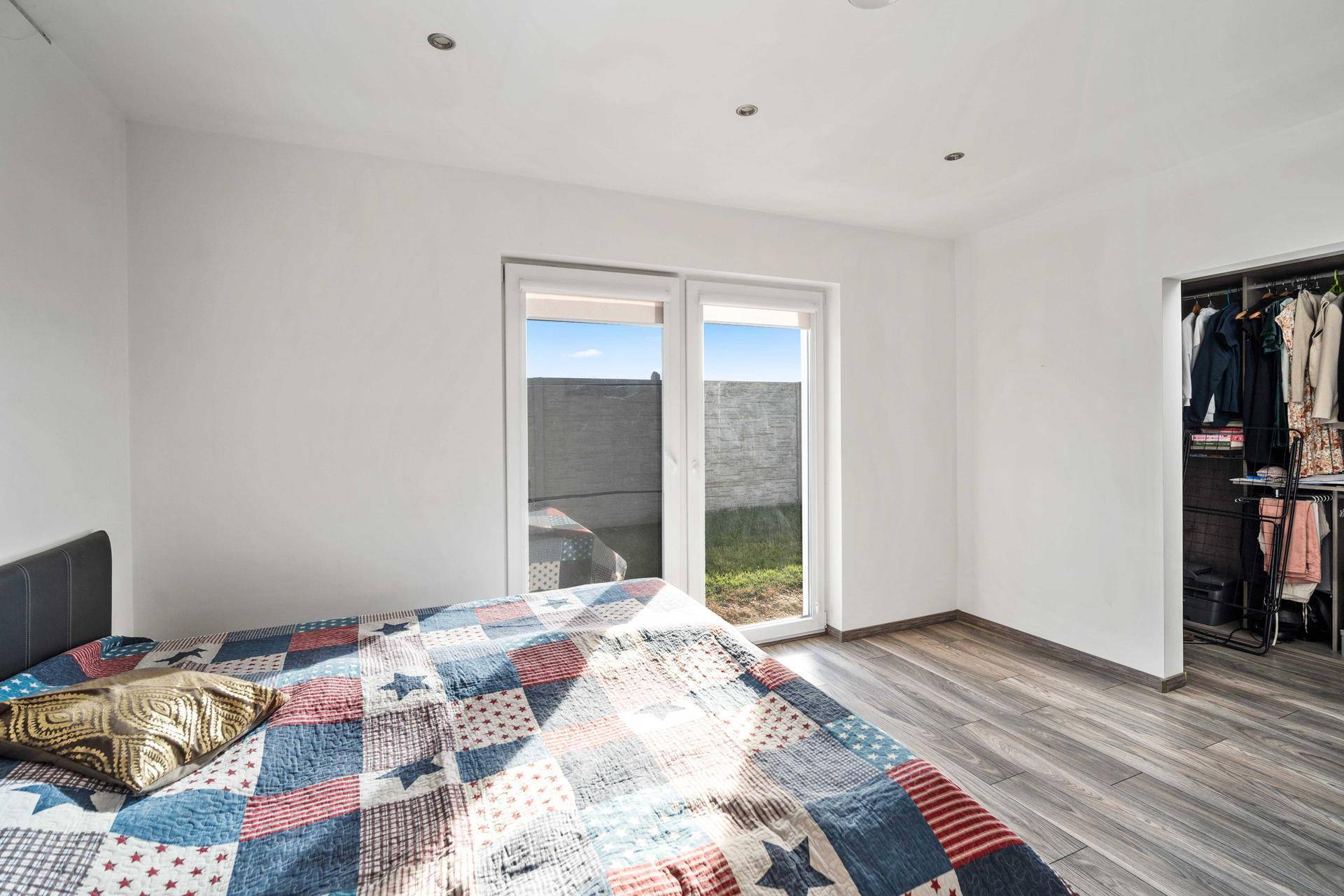 Schlafzimmer mit direktem Zugang zum Garten und praktischem Ankleidebereich.