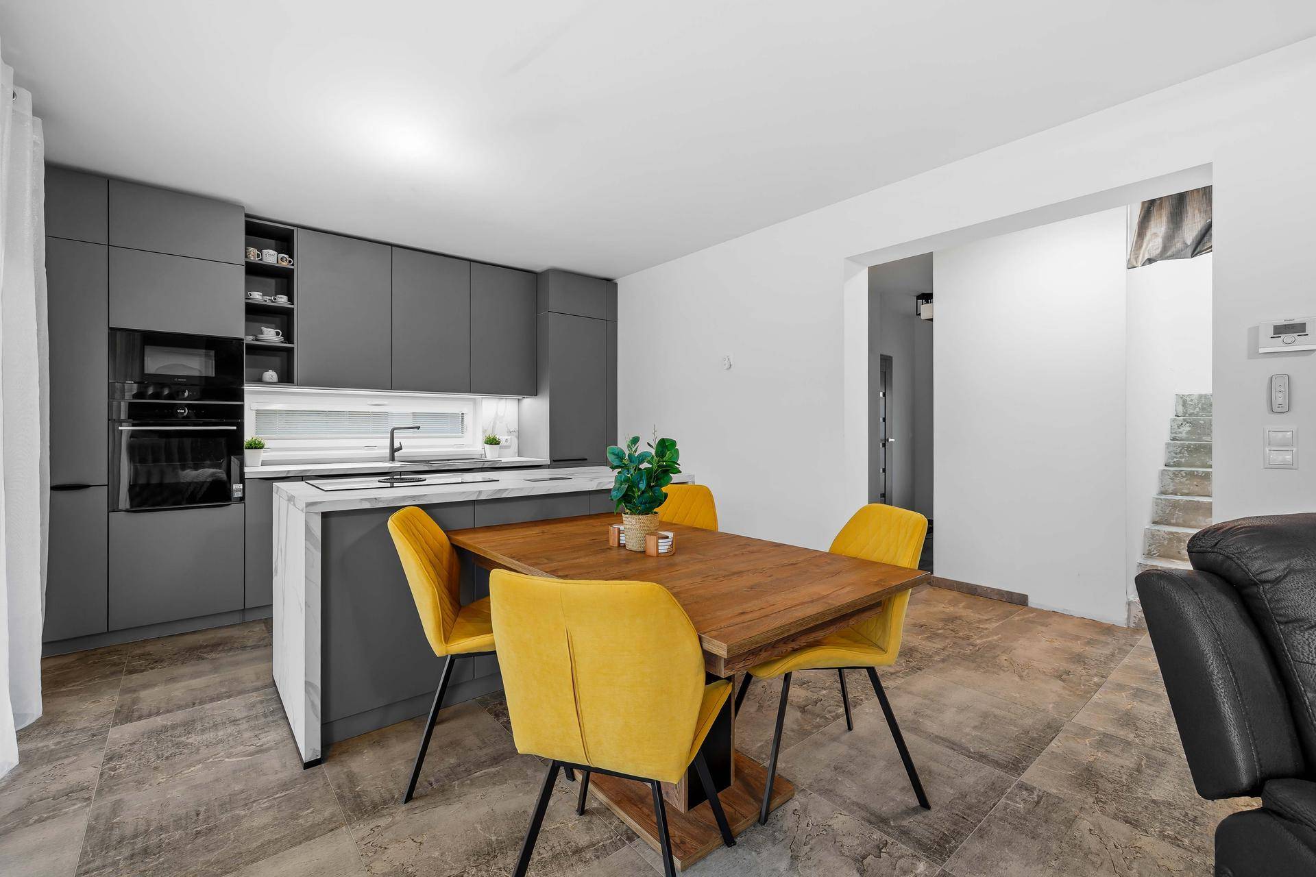 Heller Wohn- und Essbereich mit moderner Küche, Kücheninsel und Zugang zum Wohnzimmer.