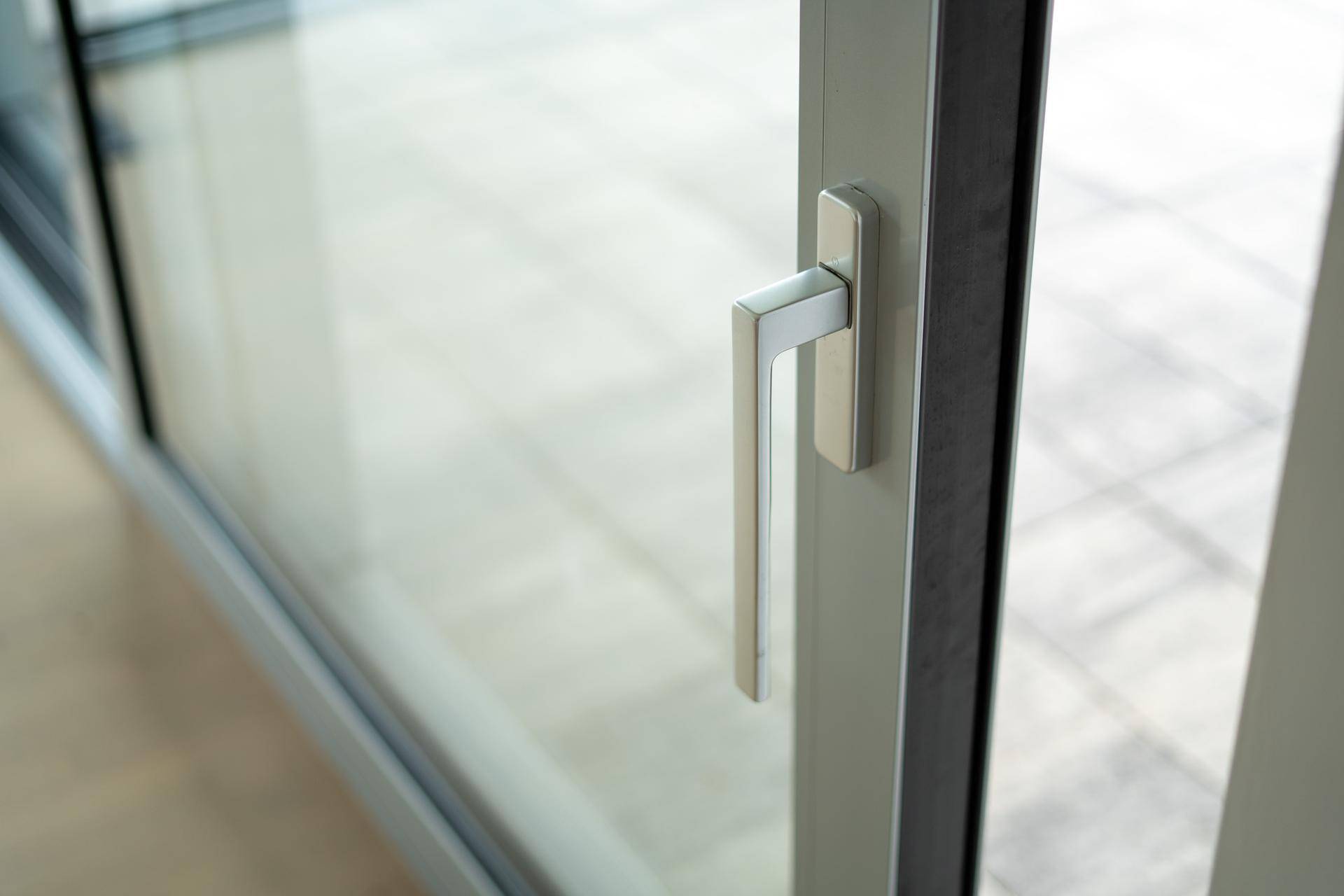 Detailaufnahme eines modernen Fenstergriffs an einem großen Schiebefenster.